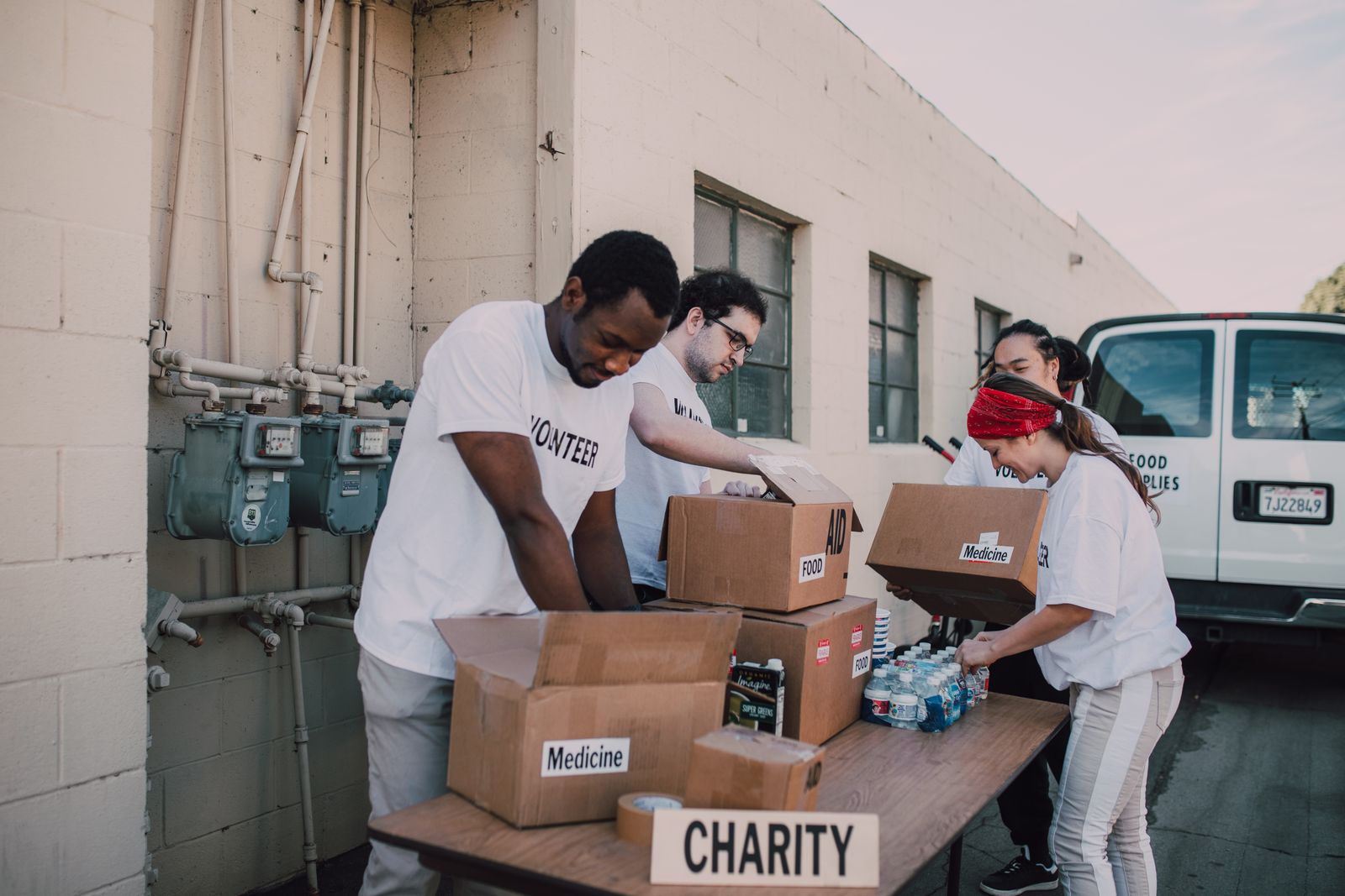 Volunteers sorting and packing donated food and supplies outdoors.